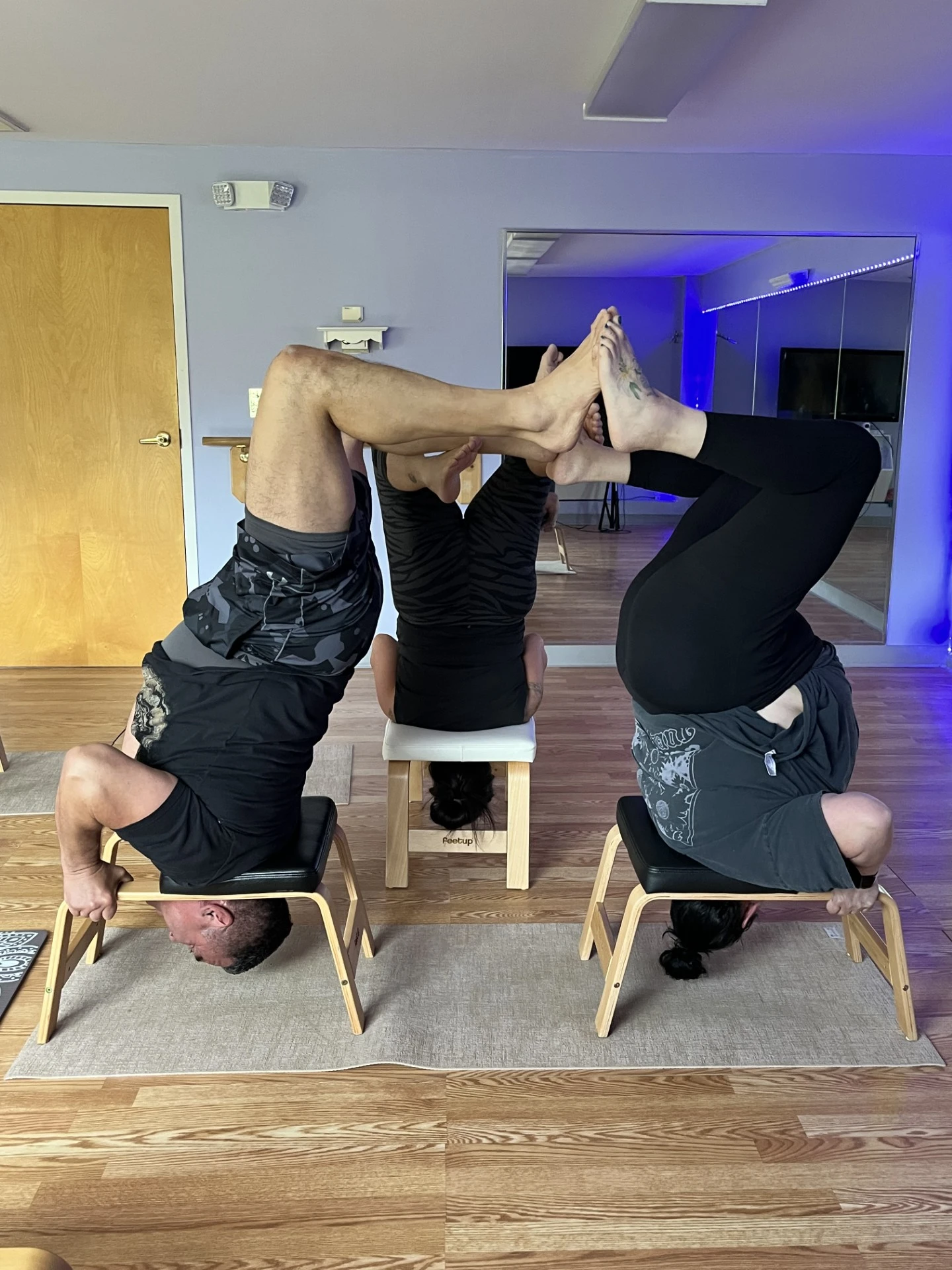 Three students practicing supported inversions on FeetUp benches at Gravity Yoga Center